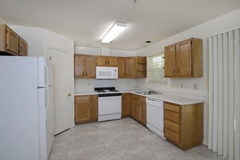 a kitchen with white appliances and wooden cabinets at Carlson Woods Townhomes, Baltimore